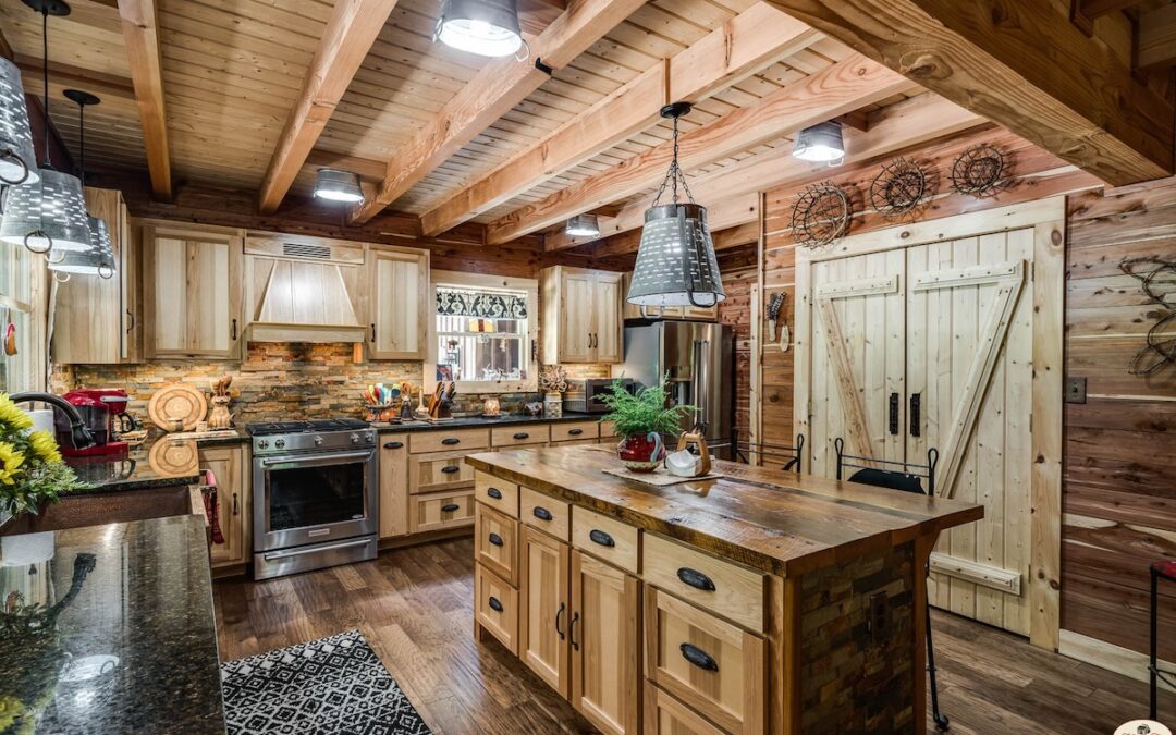 Photo of log home kitchen with wood barn doors to pantry, rustic island and shelves with very modern appliance package and modern drop lights