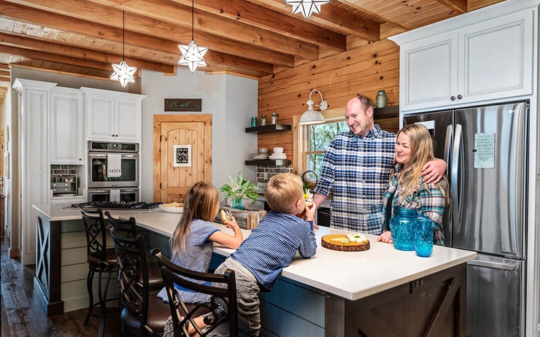 Young couple in a log home kitchen eating cookies with two small children