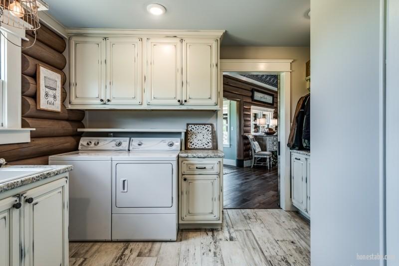 photo of laundry room with distress cabinets and wood floor and round log exterior wall